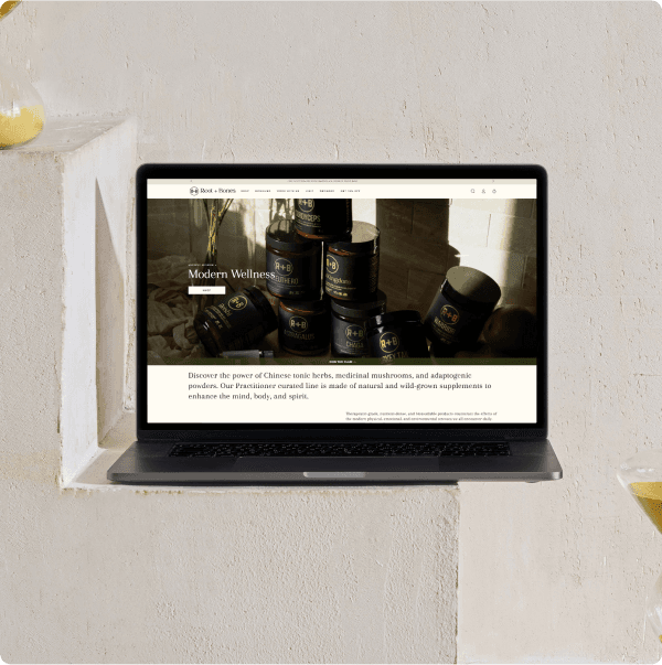 The Root + Bones homepage shown on a laptop in a sunlit alcove